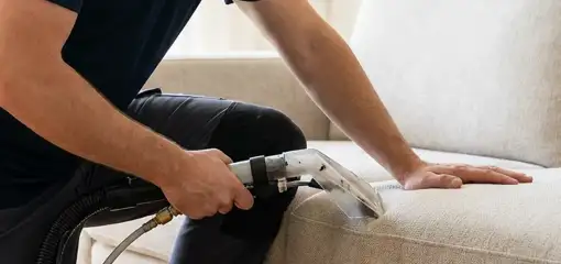Professional upholstery cleaner deep-cleaning a fabric sofa with a handheld extraction tool, Boise, ID.